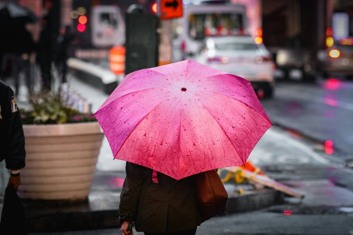 a woman walking down the sidewalk with an umbrella